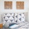 a bed with a blue and white pillow and a lamp on the side