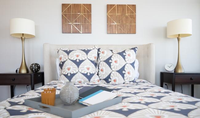 a bed with a blue and white pillow and a lamp on the side